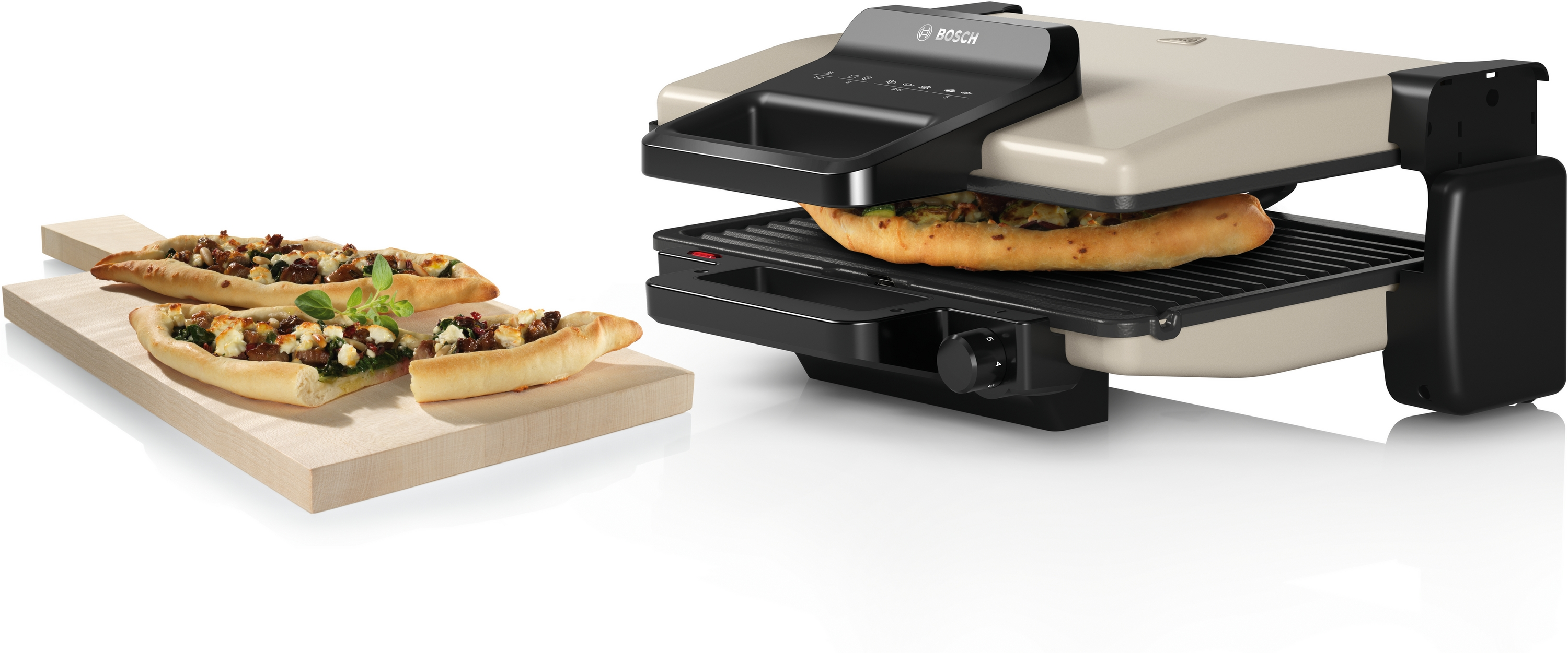 Ein Bosch Kontaktgrill mit Pizza und Pide daneben auf einem Holzbrett.