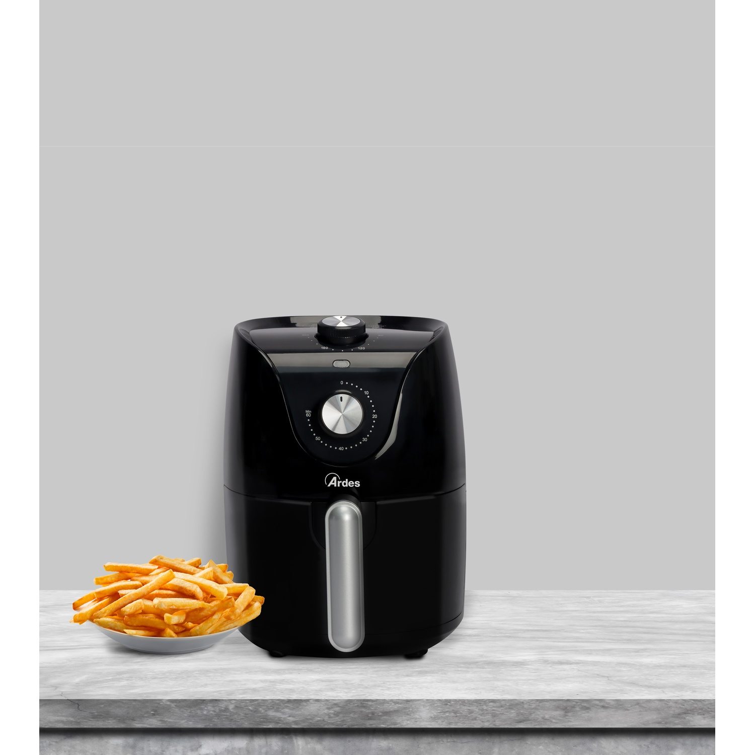 Una friggitrice ad aria nera accanto a una ciotola di patatine fritte.