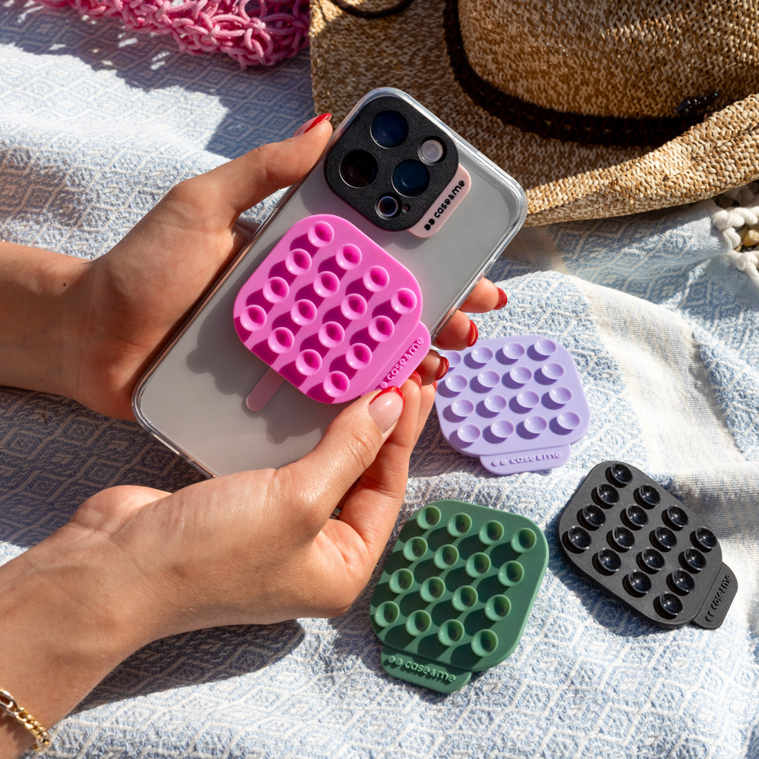Hands hold a phone with a pink popsocket; purple, green, black holders nearby.