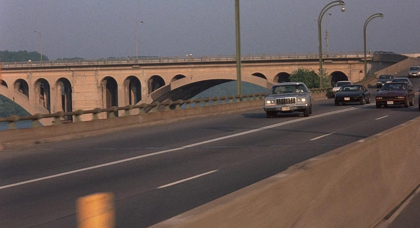 Autos fahren auf einer Autobahn unter einer Steinbrücke mit Bögen. Morgendlicher Himmel.