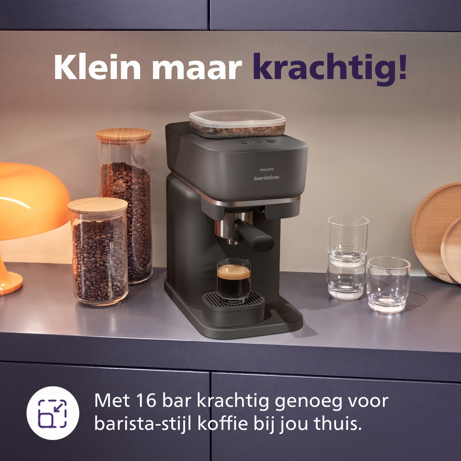Een donkere espressomachine met twee glazen potten koffiebonen ernaast.