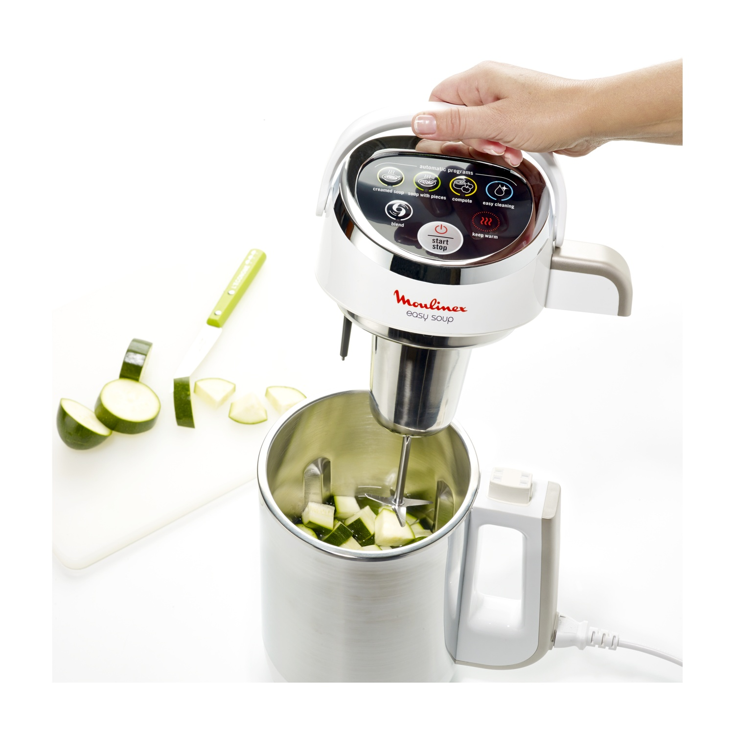 Una macchina per zuppe Moulinex Easy Soup con zucchine nel contenitore e tagliere.