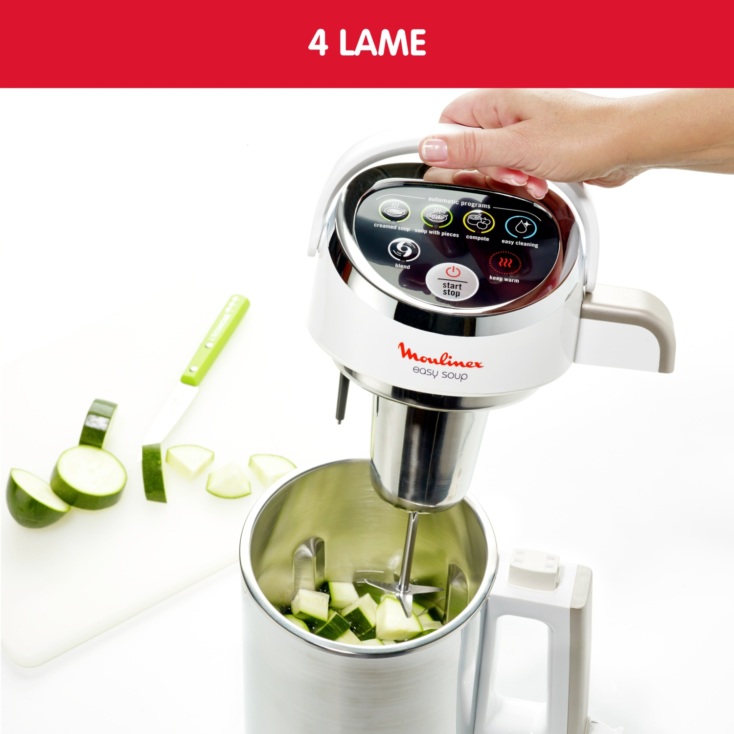 Una mano tiene un frullatore bianco sopra una pentola con zucchine a dadini.