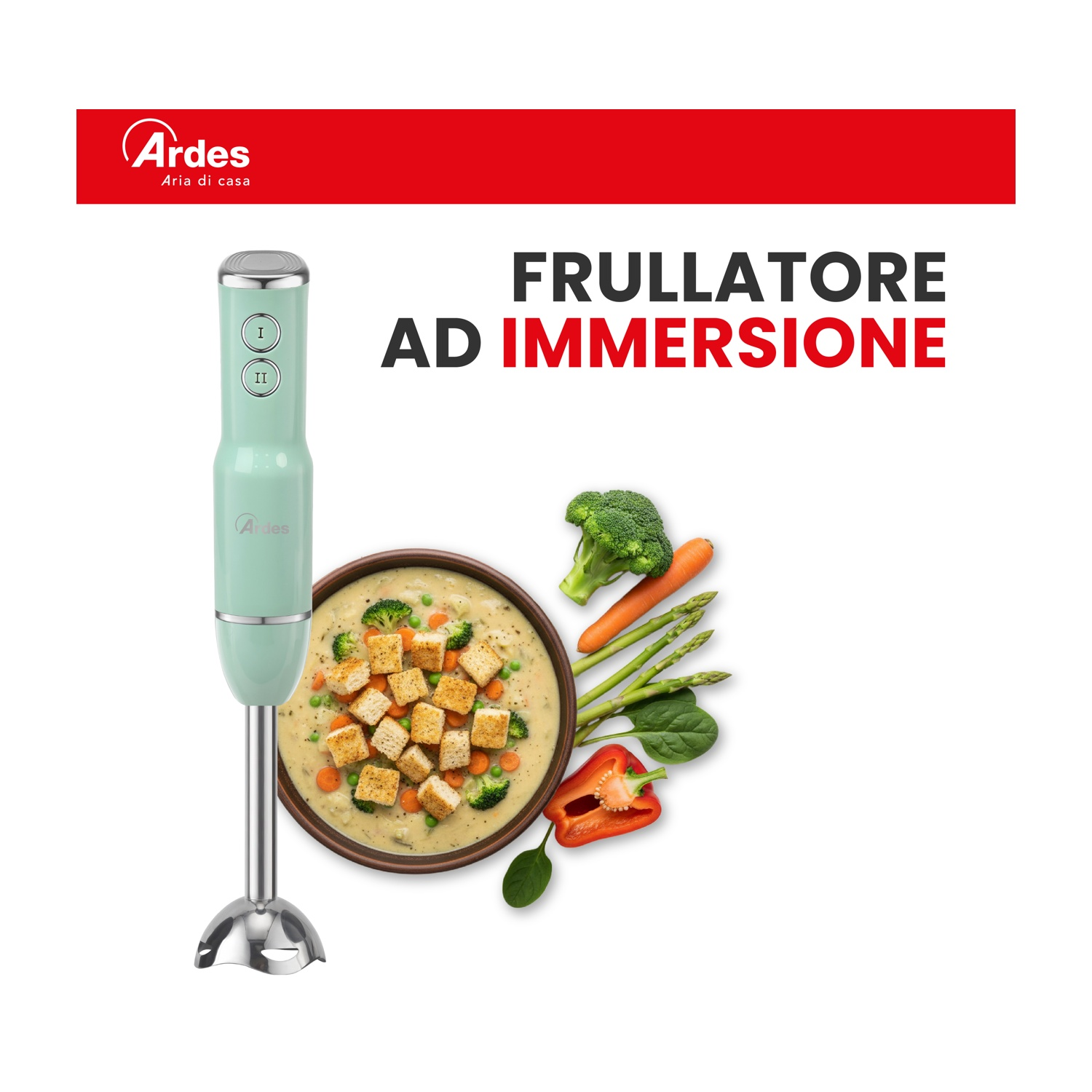 Un frullatore a immersione verde accanto a una ciotola di zuppa e verdure fresche.