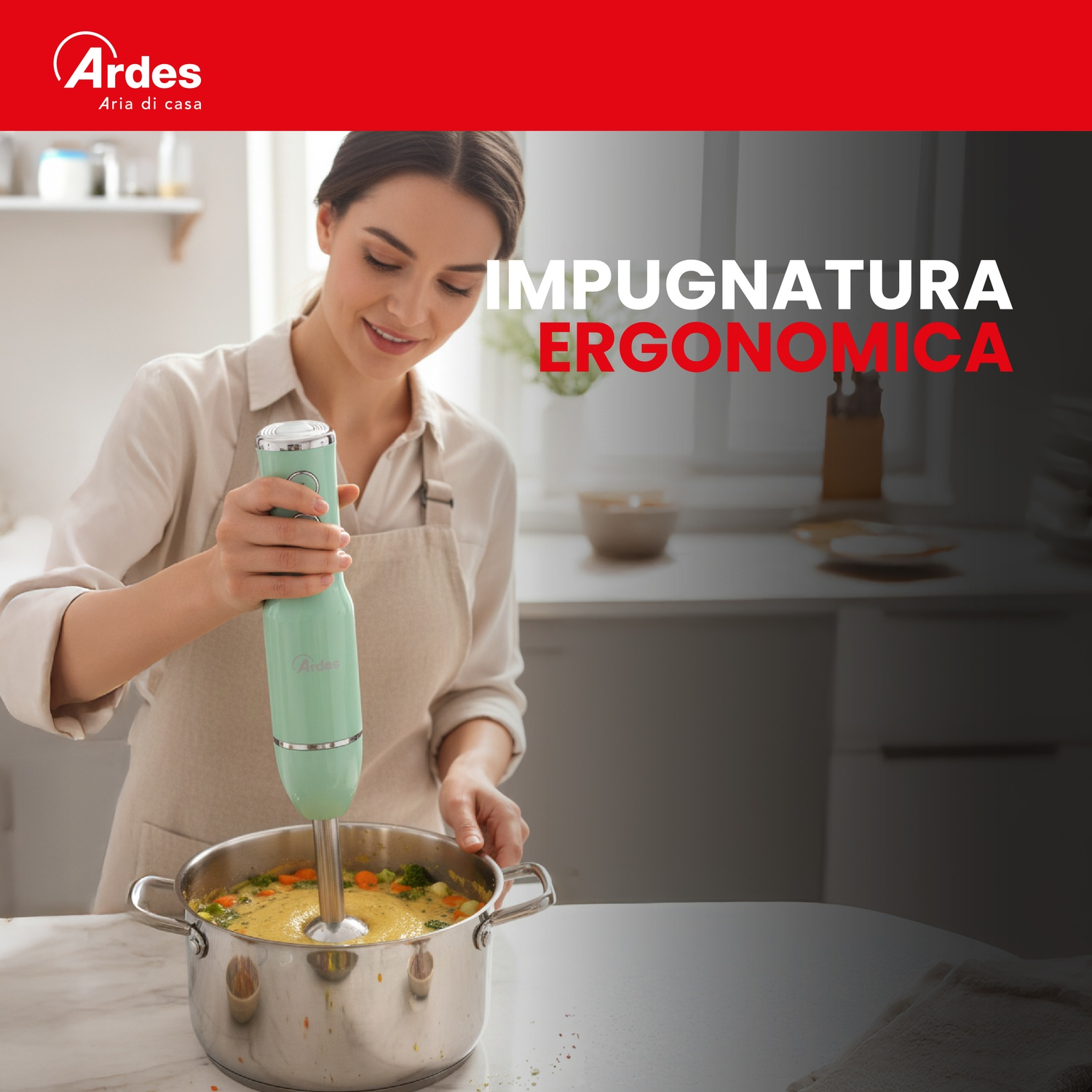 Una donna frulla una zuppa in una pentola con un frullatore a immersione verde.
