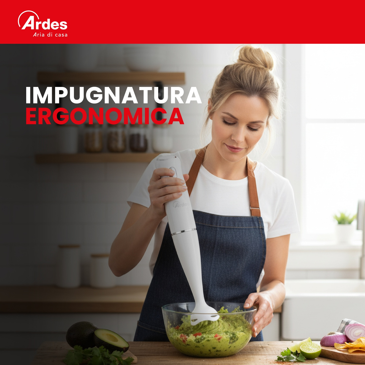 Una donna frulla guacamole in una ciotola con un frullatore a immersione. Ingredienti vicini.