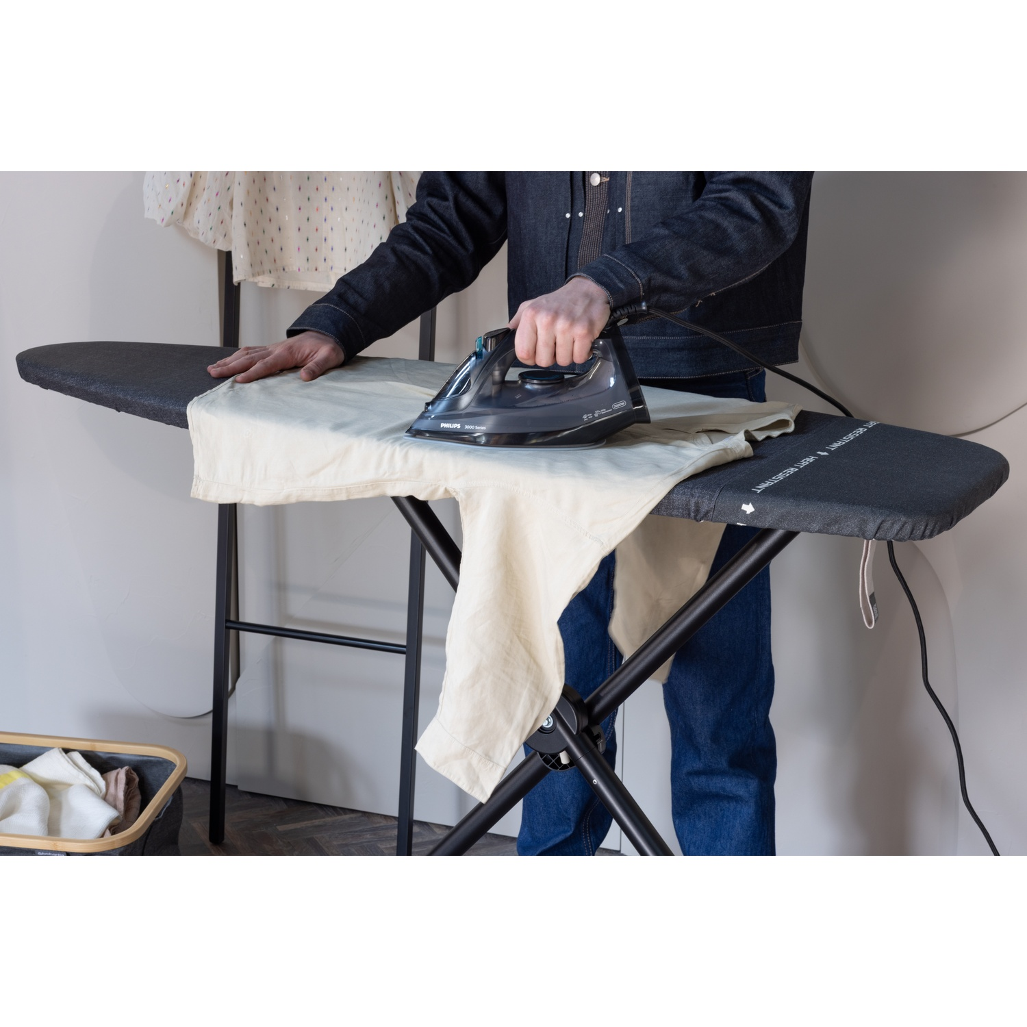 Een persoon strijkt een lichtgekleurd kledingstuk op een strijkplank.