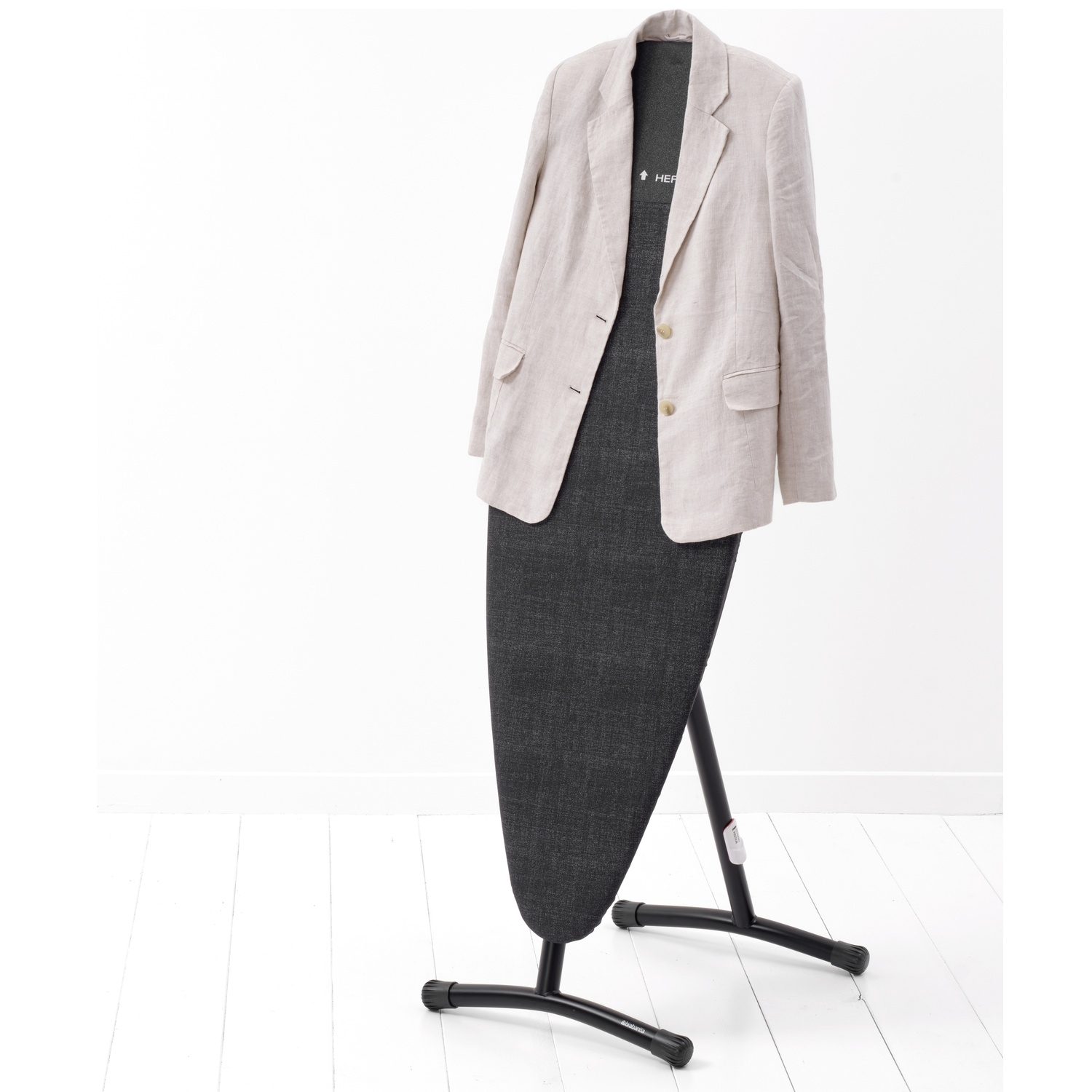 Een lichtbeige linnen blazer hangt over een donker strijkijzer.
