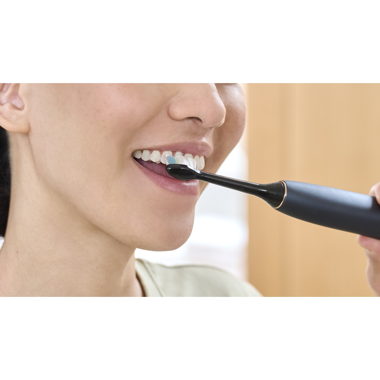 Una donna si lava i denti con uno spazzolino elettrico.