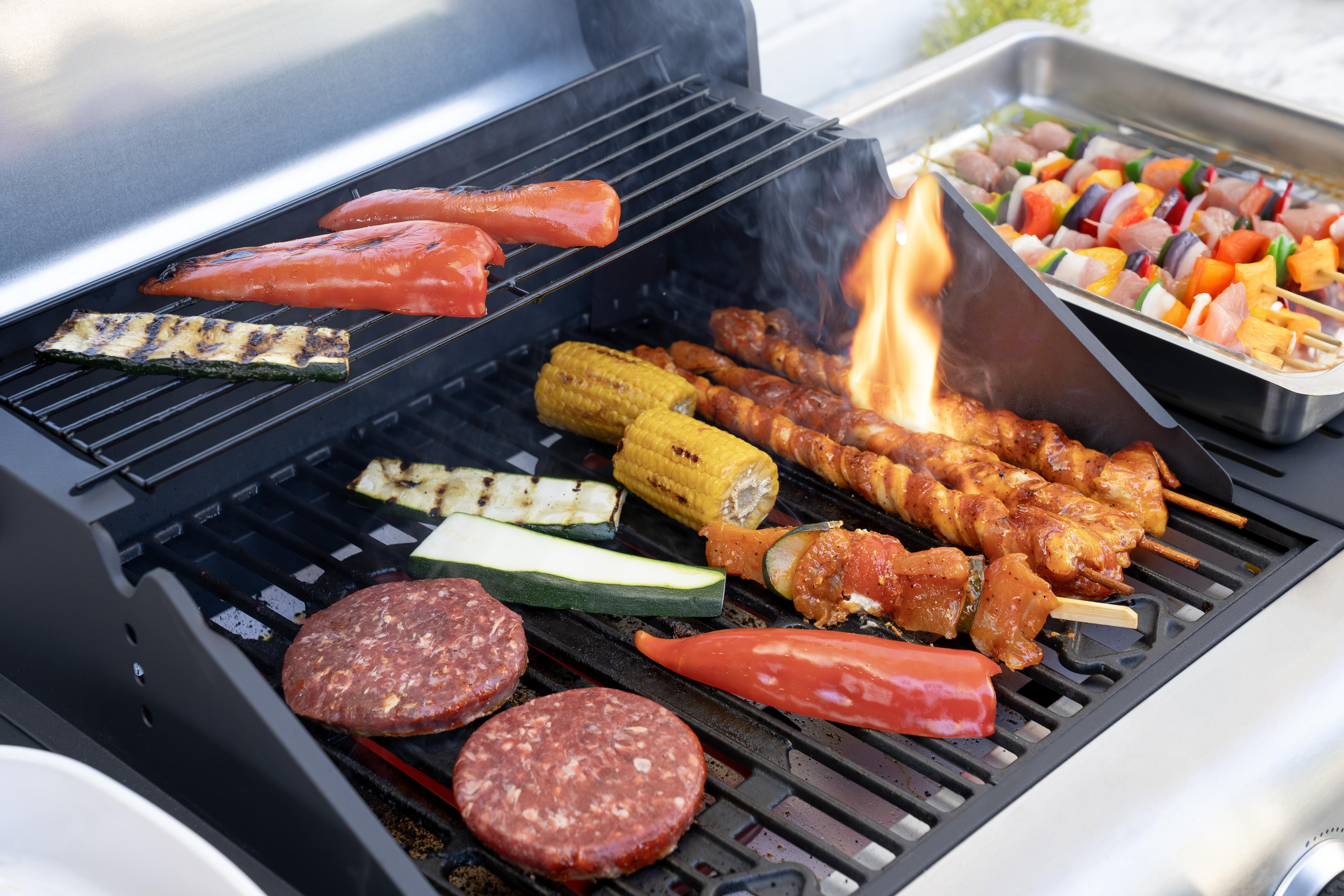 Fleischspieße, Maiskolben, Paprika und Zucchini auf einem Grill.