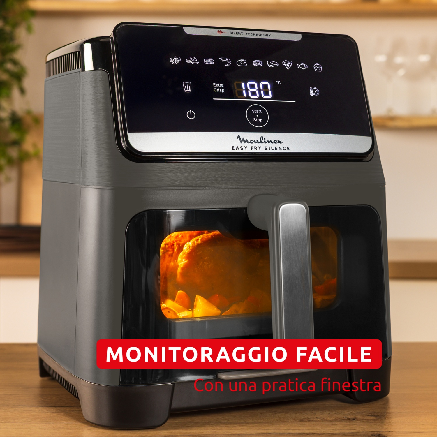 Una friggitrice ad aria Moulinex grigia con pollo all'interno, display 180.