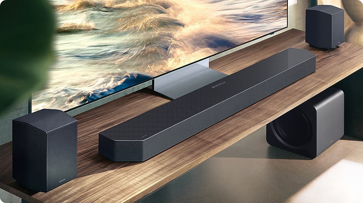 Ein schwarzer Soundbar mit zwei Lautsprechern und einem Subwoofer vor einem Fernseher.
