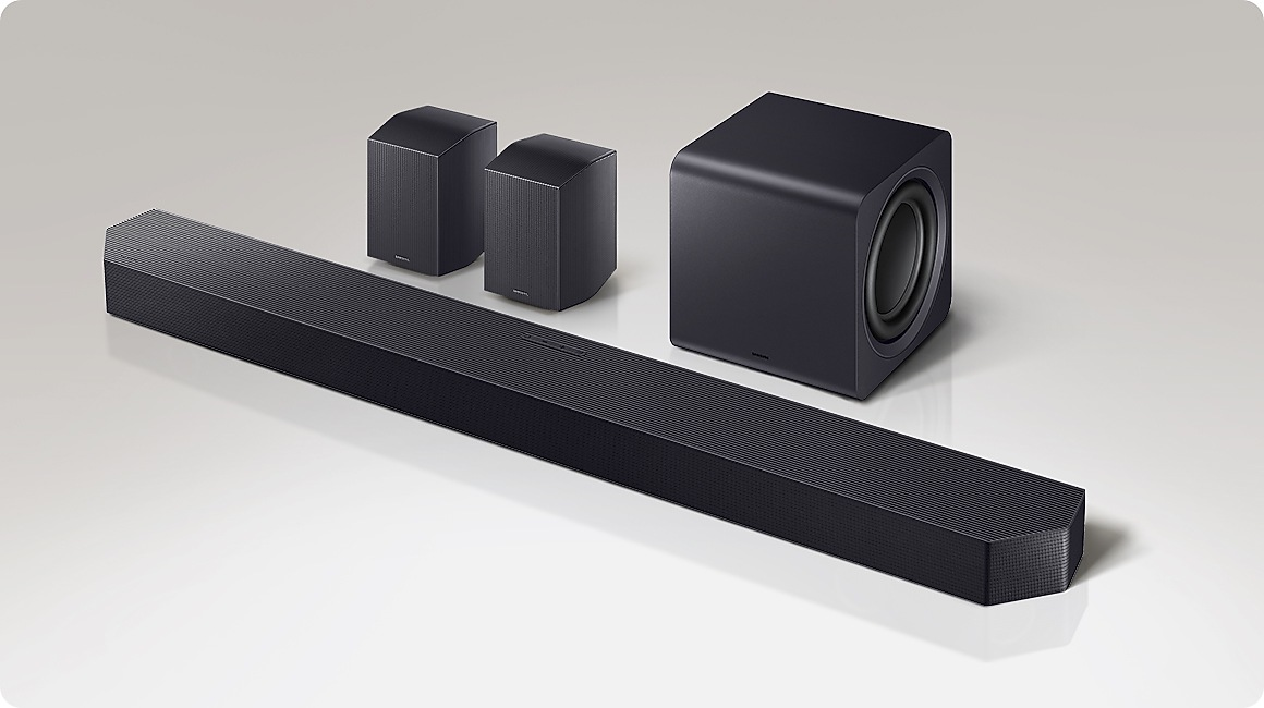 Schwarze Soundbar, zwei Satellitenlautsprecher und ein Subwoofer auf grauem Hintergrund.