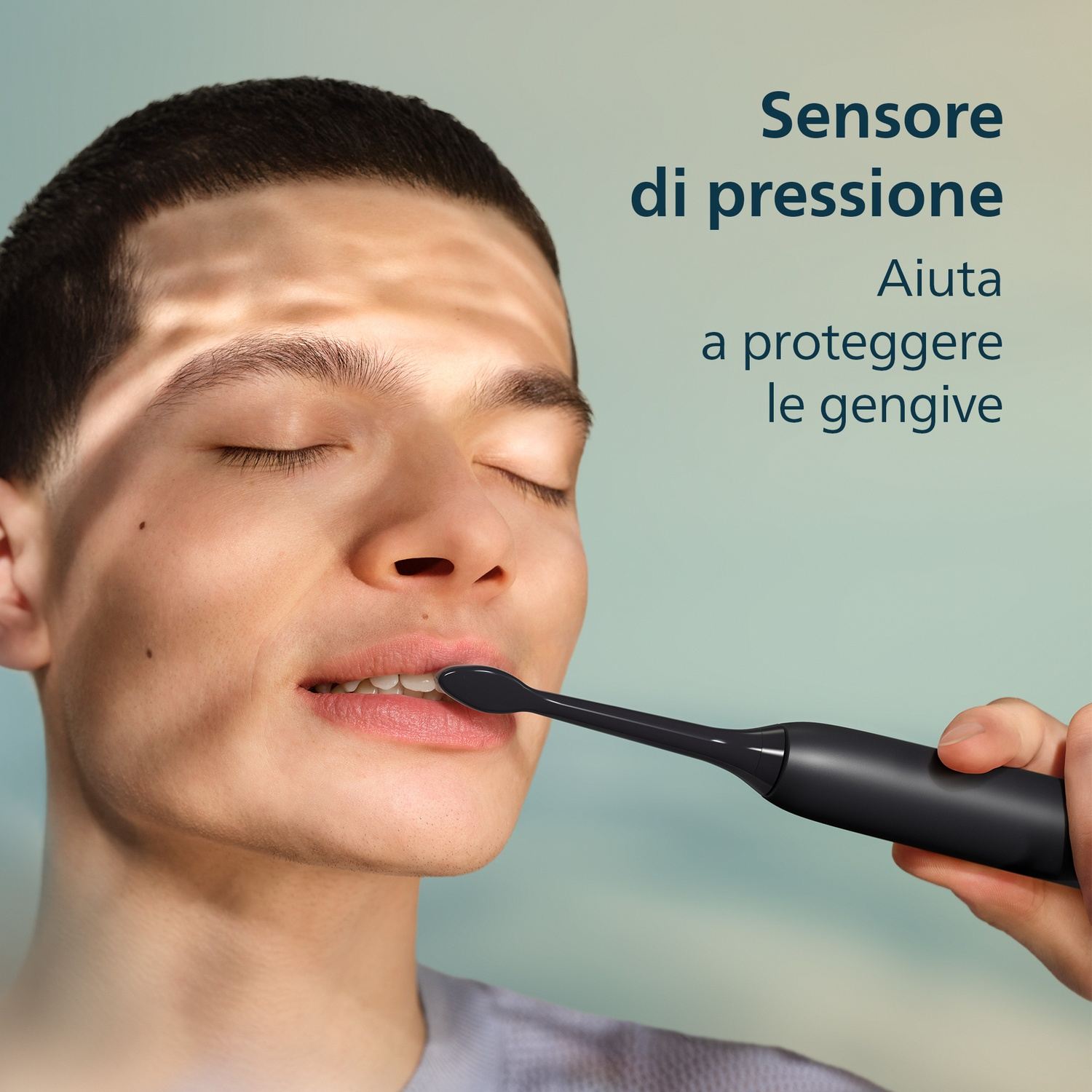Uomo si lava i denti con spazzolino elettrico nero. Pressione delicata.