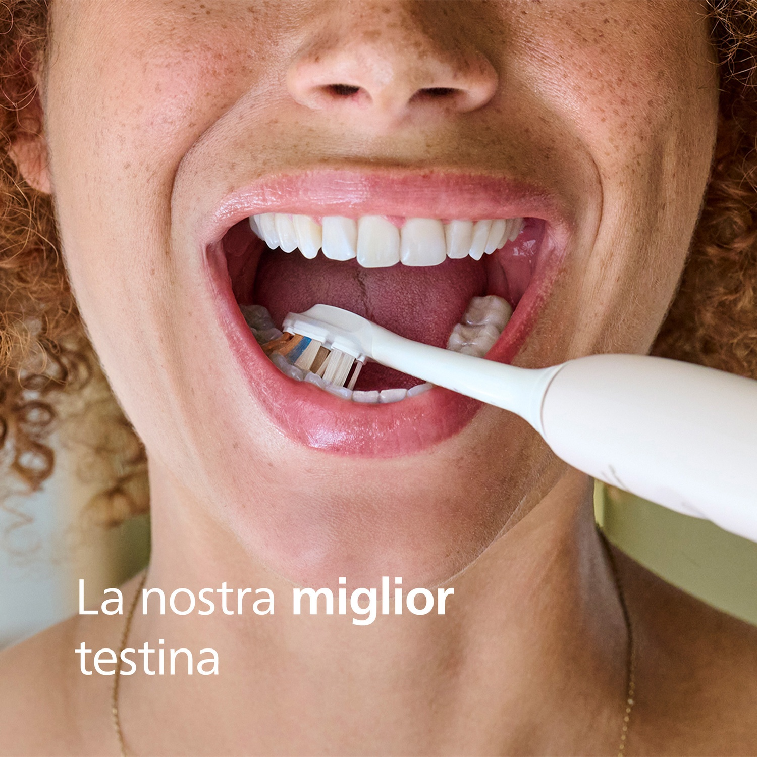 Primo piano di una donna che si lava i denti con uno spazzolino elettrico.