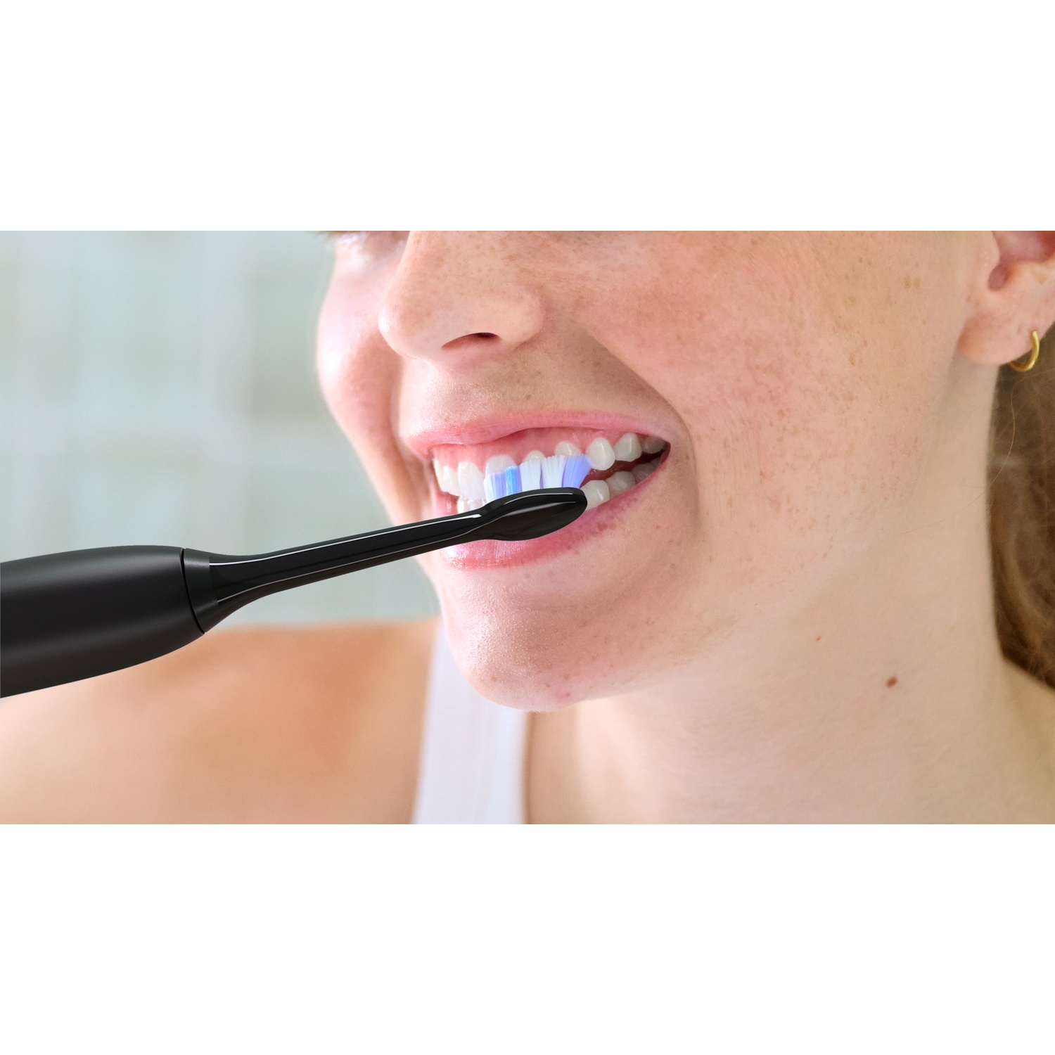 Primo piano di una donna che si lava i denti con uno spazzolino elettrico nero.