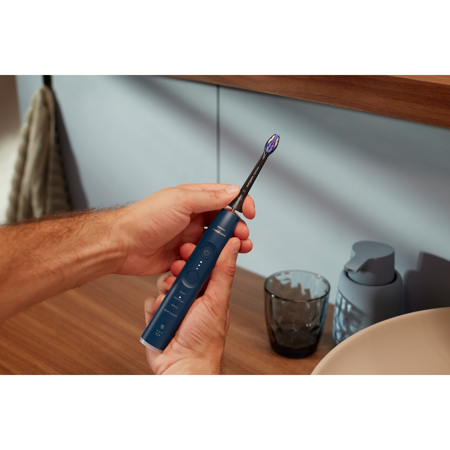 Una persona tiene uno spazzolino elettrico blu scuro con setole viola.