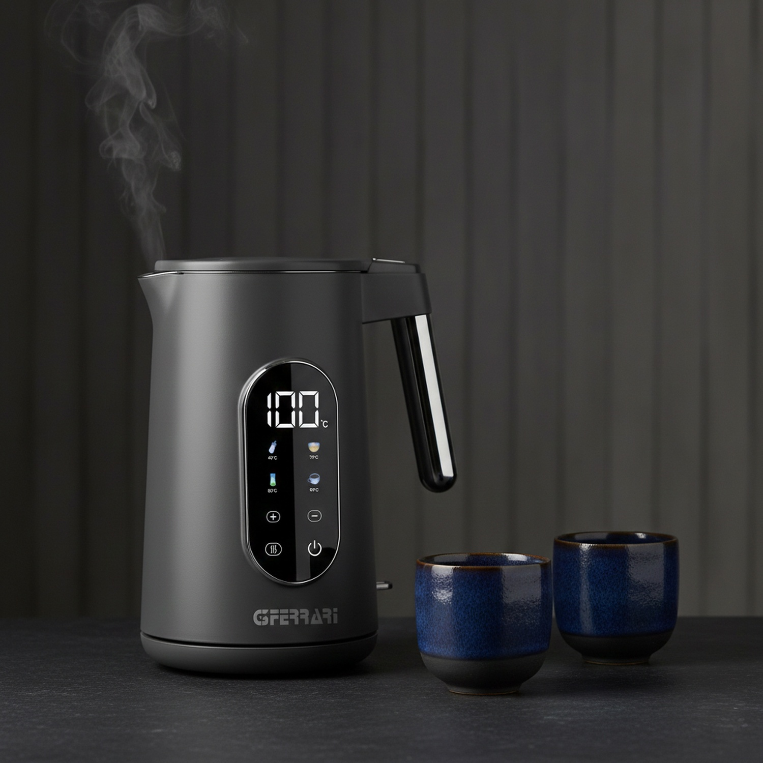 Bollitore grigio con display digitale che fa bollire l'acqua, due tazze blu accanto.