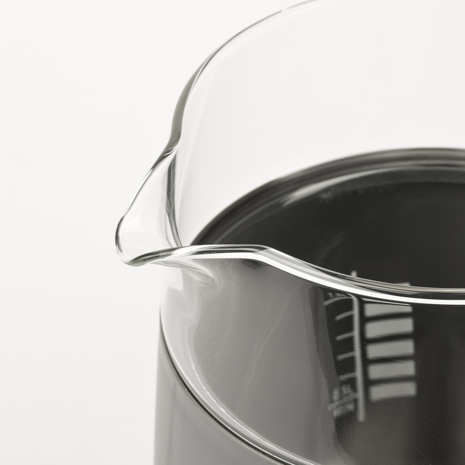 Primo piano di un becher di vetro con liquido scuro e segni di misurazione.