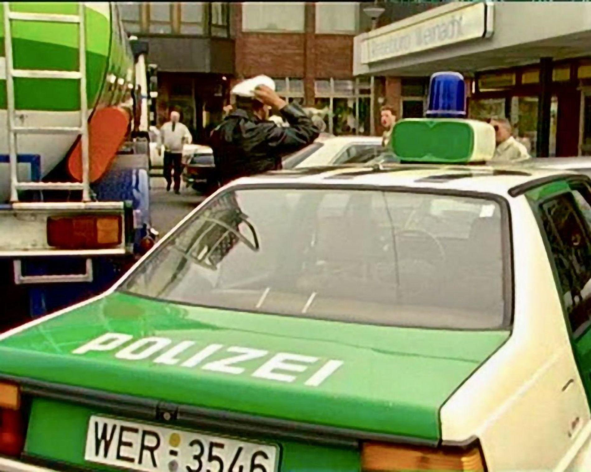 Ein Polizeiauto mit grünen und weißen Akzenten steht neben einem Tankwagen.