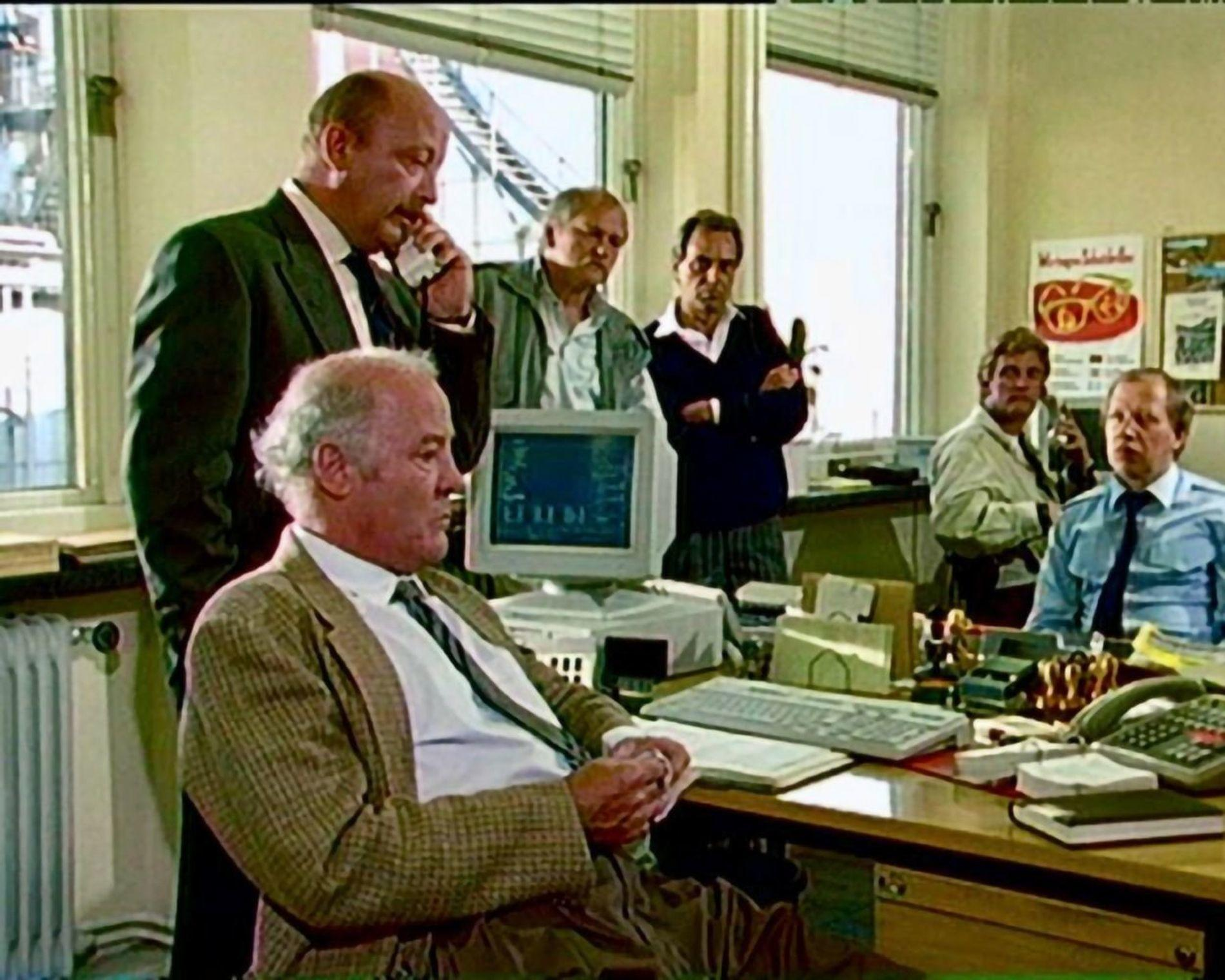 Männer in einem Büro, einer telefoniert, andere schauen auf einen Monitor.