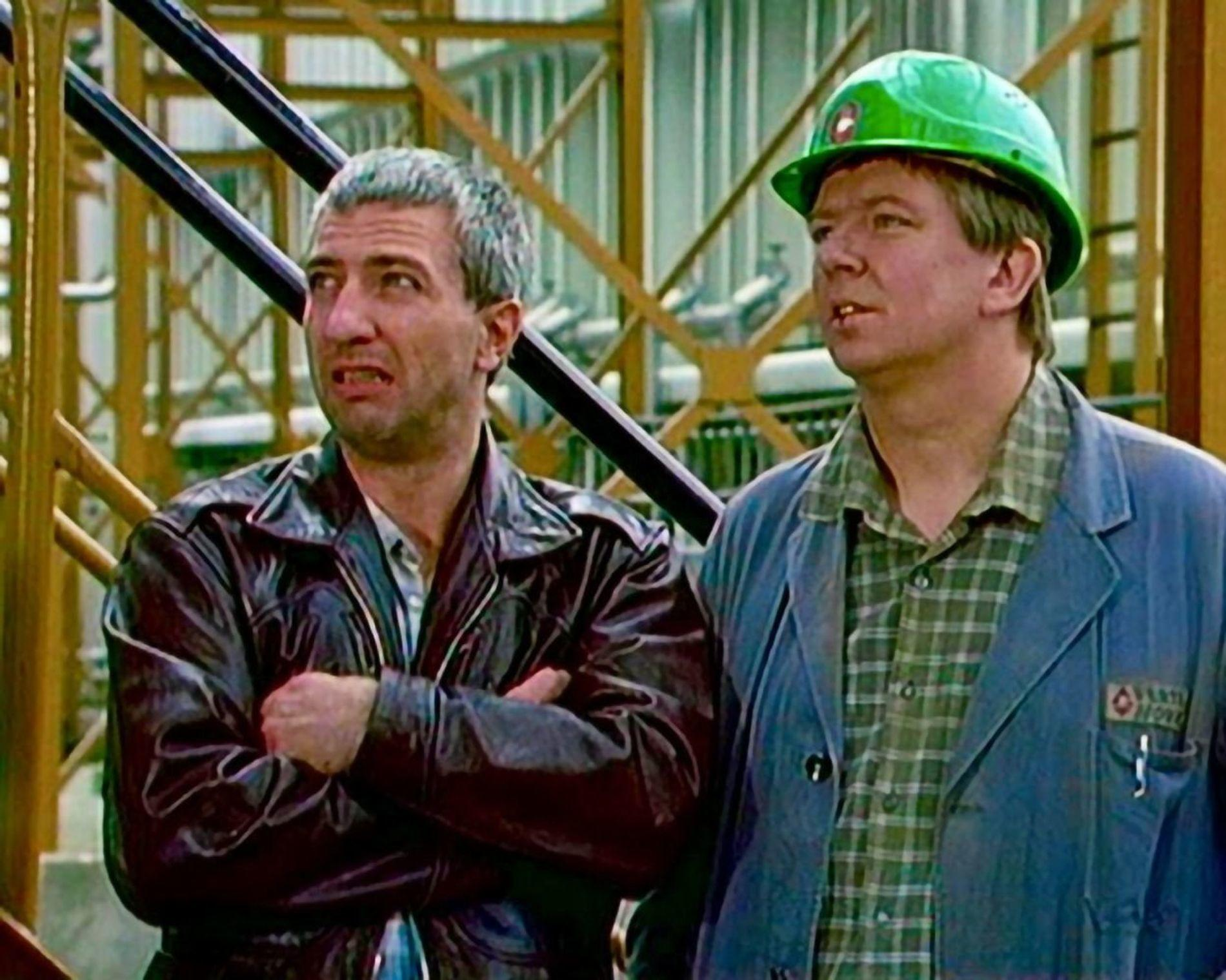 Zwei Männer auf einer Baustelle. Einer trägt einen grünen Helm.
