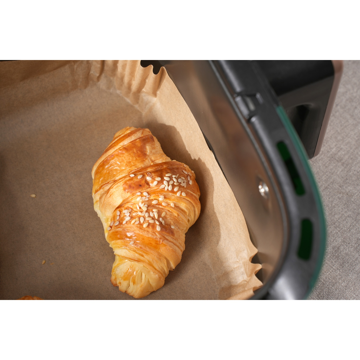 Un croissant dorato con semi di sesamo su carta da forno.