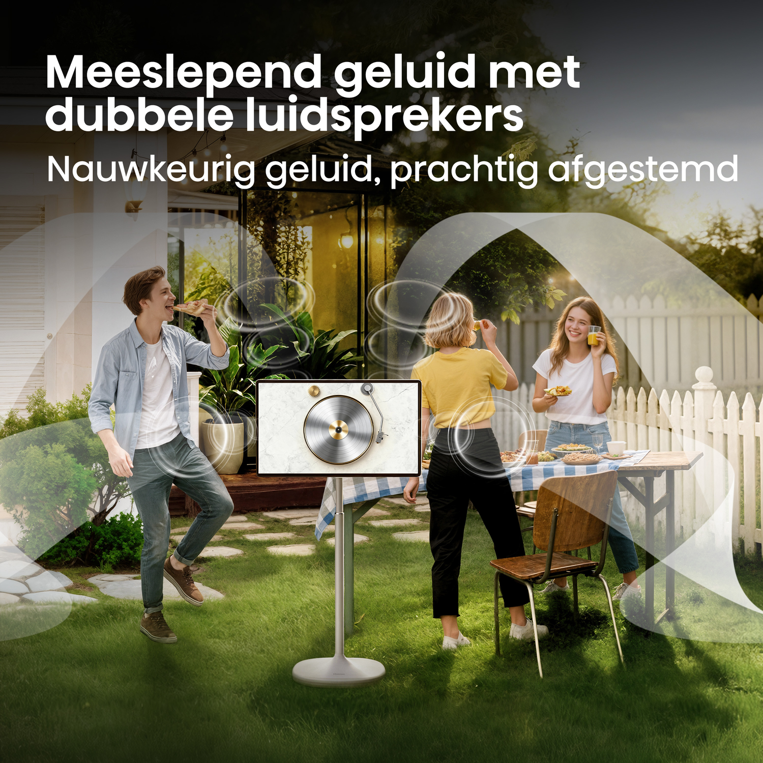 Three people in garden, one eating pizza, two at table, screen shows turntable.