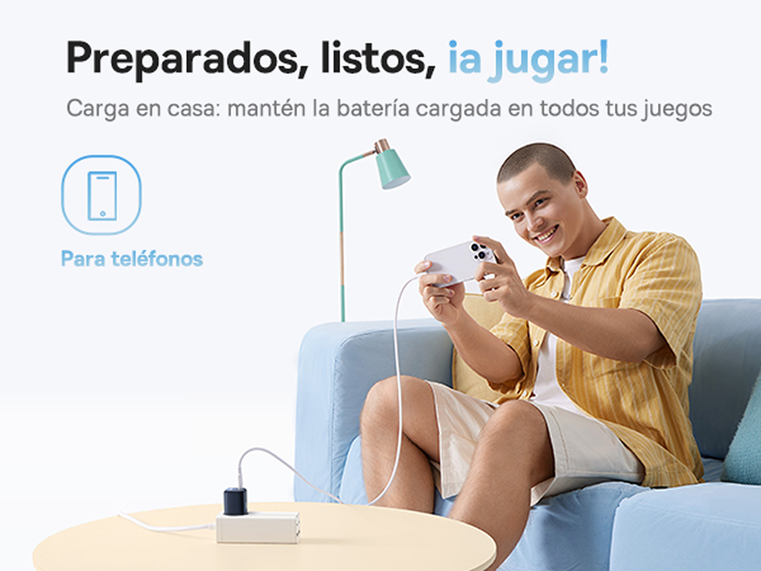 Un hombre juega en un teléfono conectado a un cargador, sentado en un sofá.