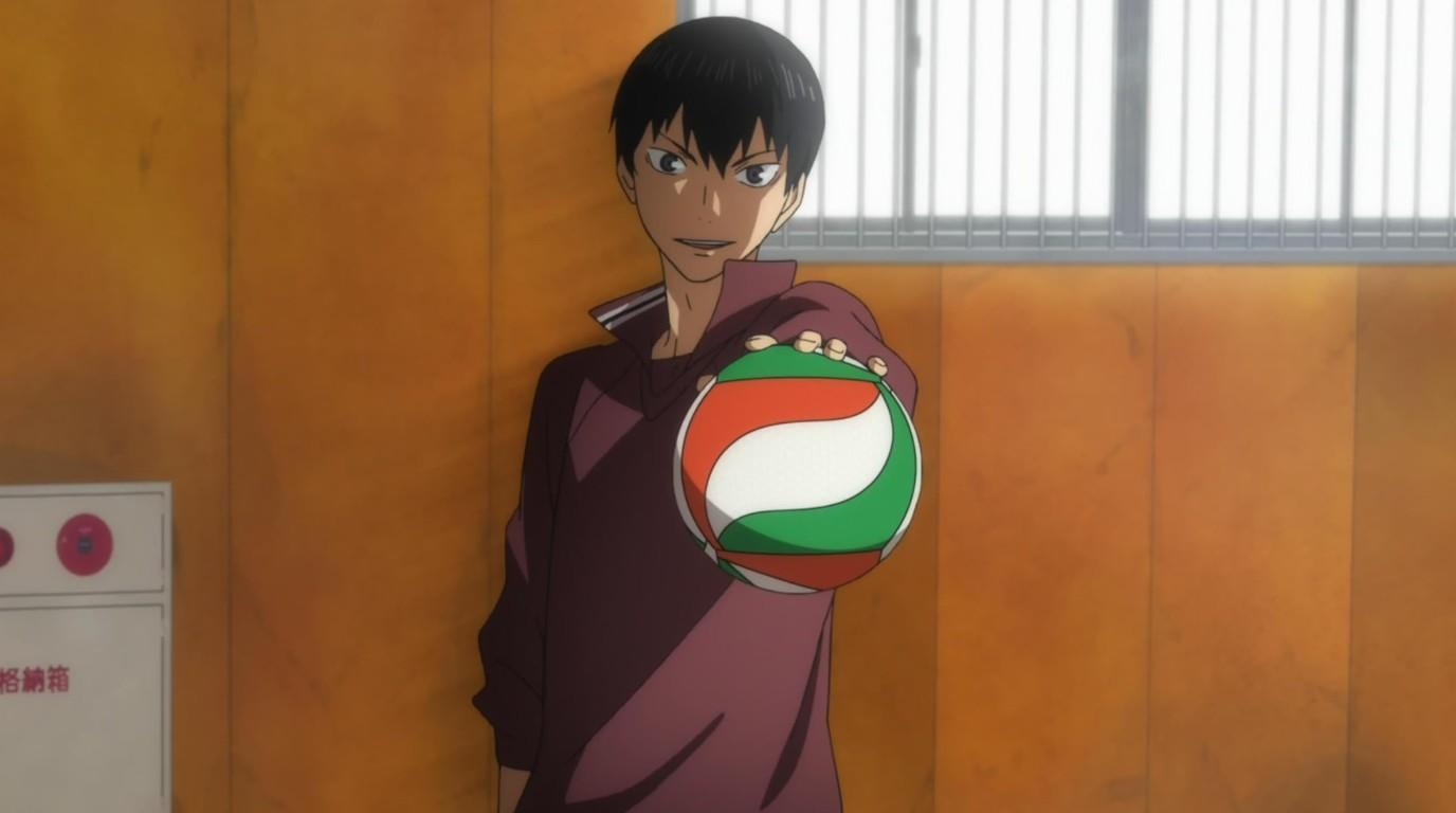 Ein Junge mit schwarzen Haaren hält einen Volleyball mit roten, weißen und grünen Streifen.