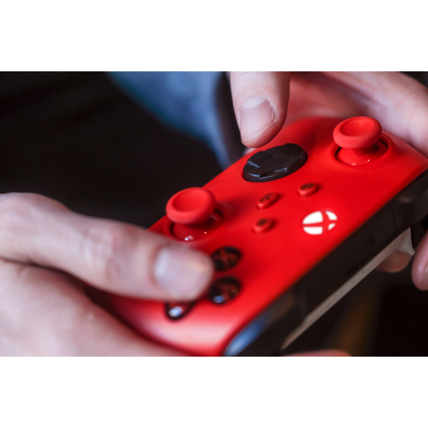 Controller Xbox rosso con pulsanti neri, tenuto dalle mani.