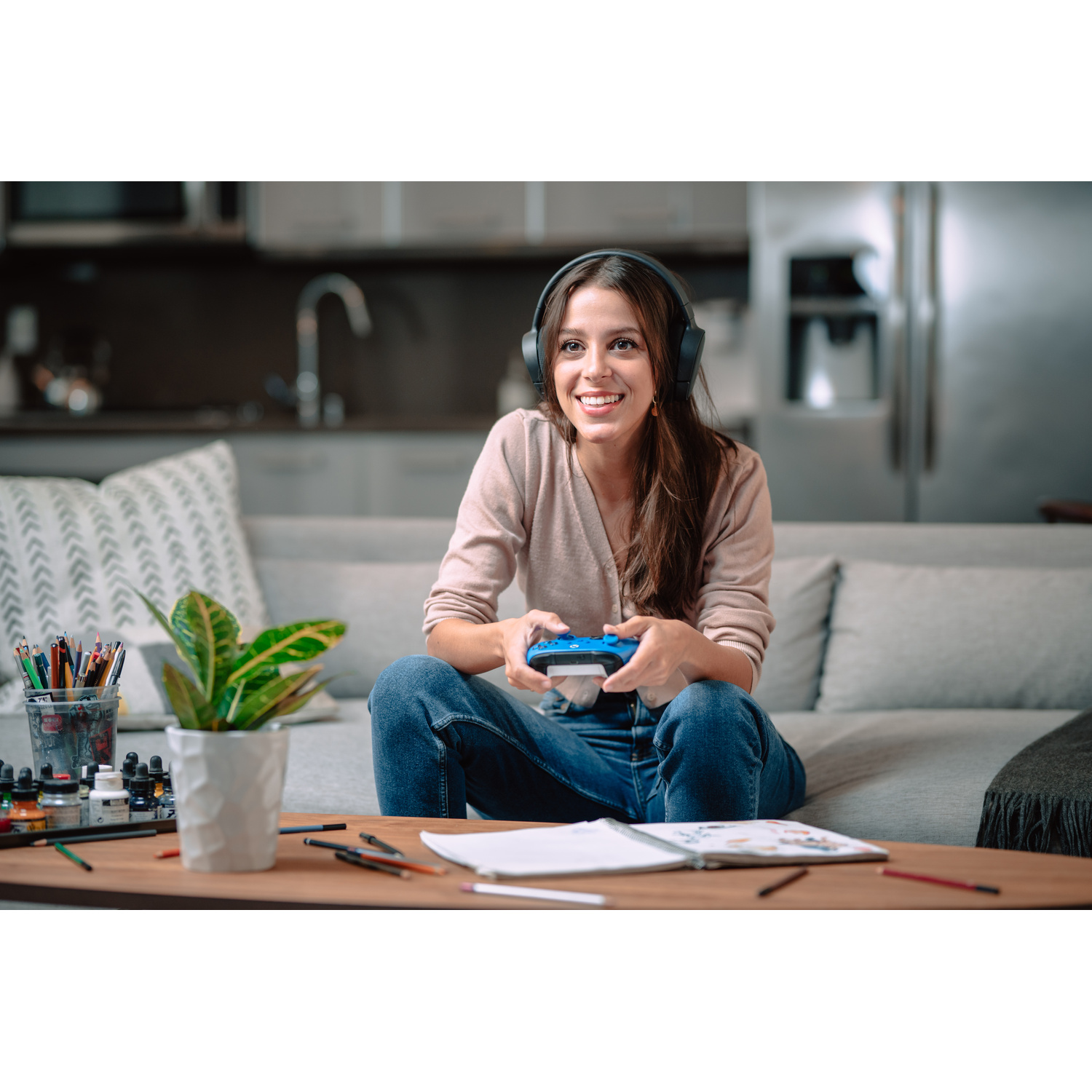 Una donna con cuffie gioca con un controller blu in un soggiorno.