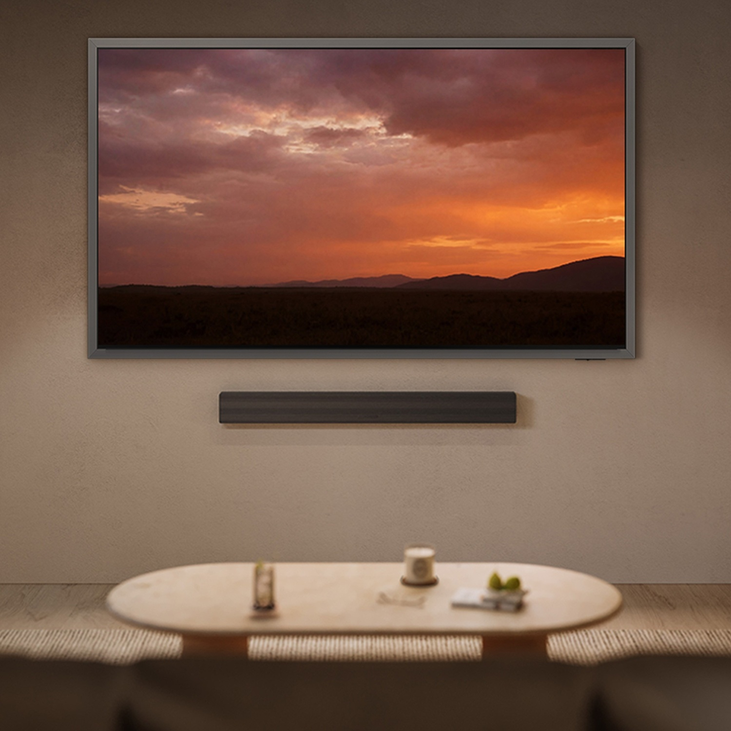Un televisore mostra un tramonto sulle colline. Un tavolino è di fronte.