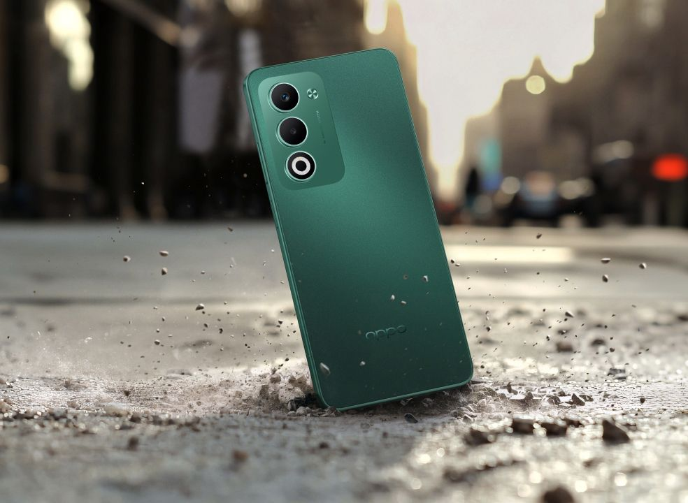 Zielony smartfon z trzema aparatami leży na kamienistym podłożu.