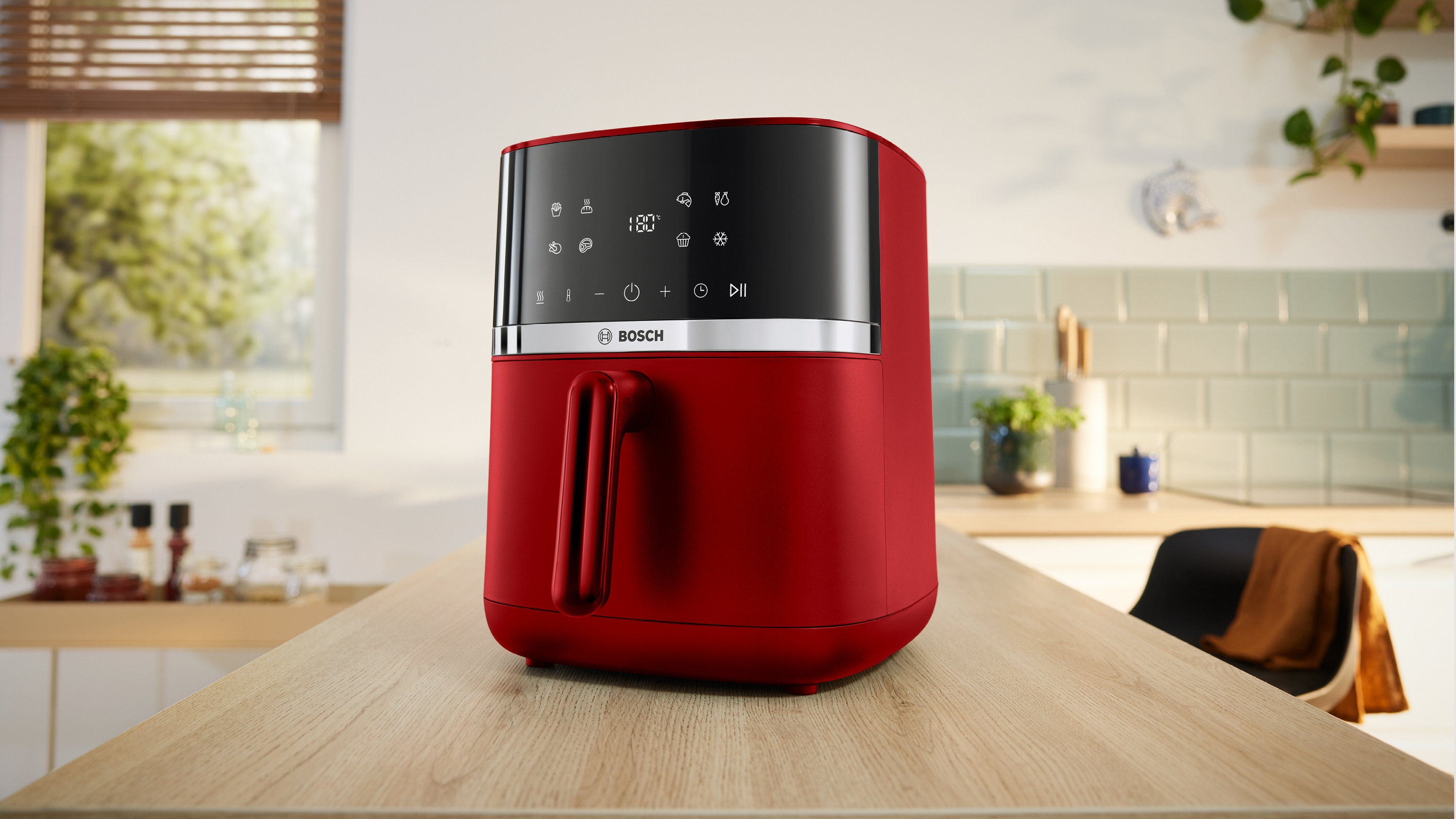 Rote Bosch Heißluftfritteuse mit digitalem Display auf einem Holztisch.