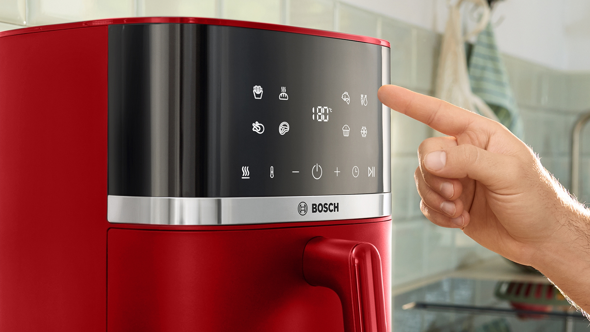Rote Heißluftfritteuse mit Touchscreen, auf den ein Finger tippt.