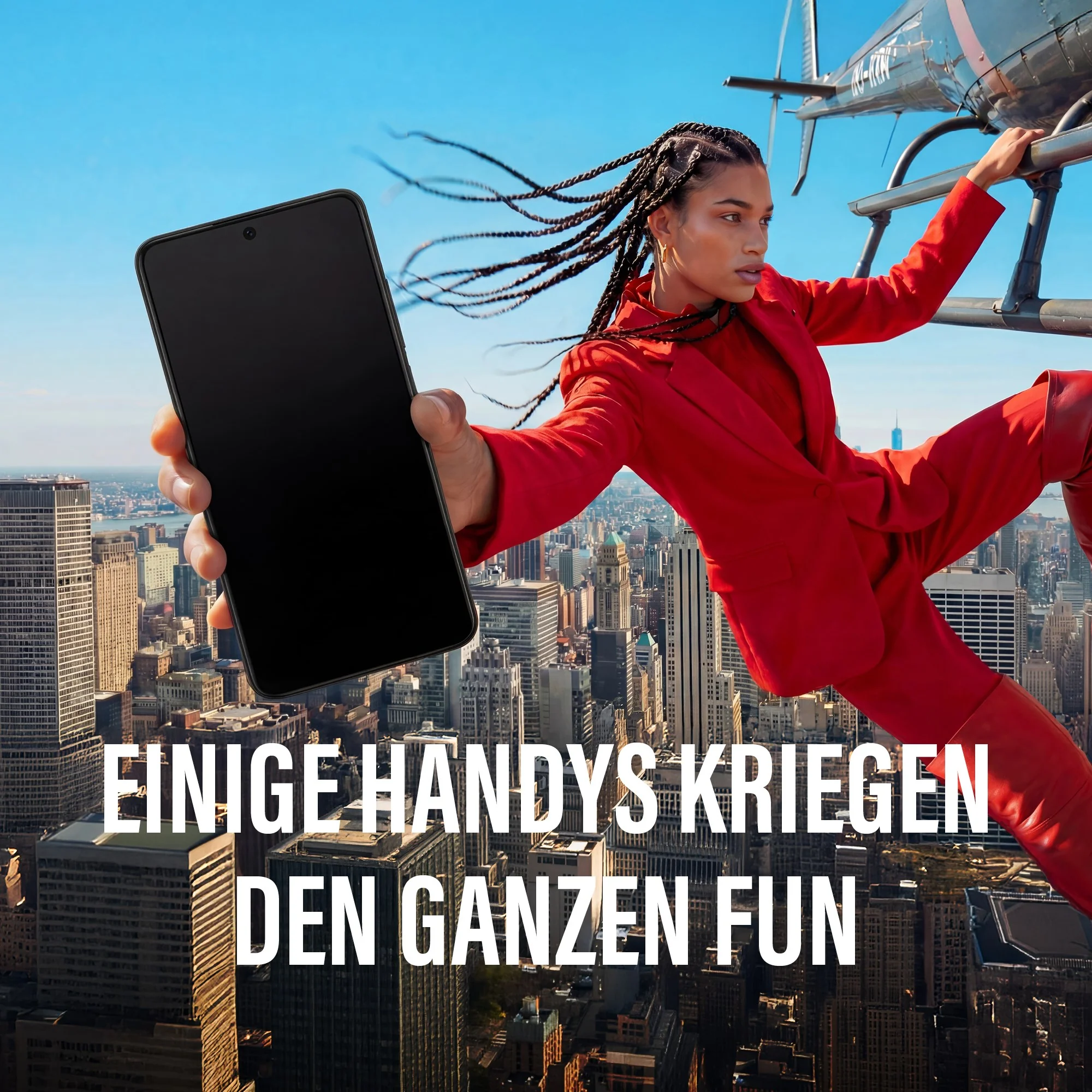 Una donna in rosso tiene un telefono davanti a uno skyline cittadino con un elicottero.