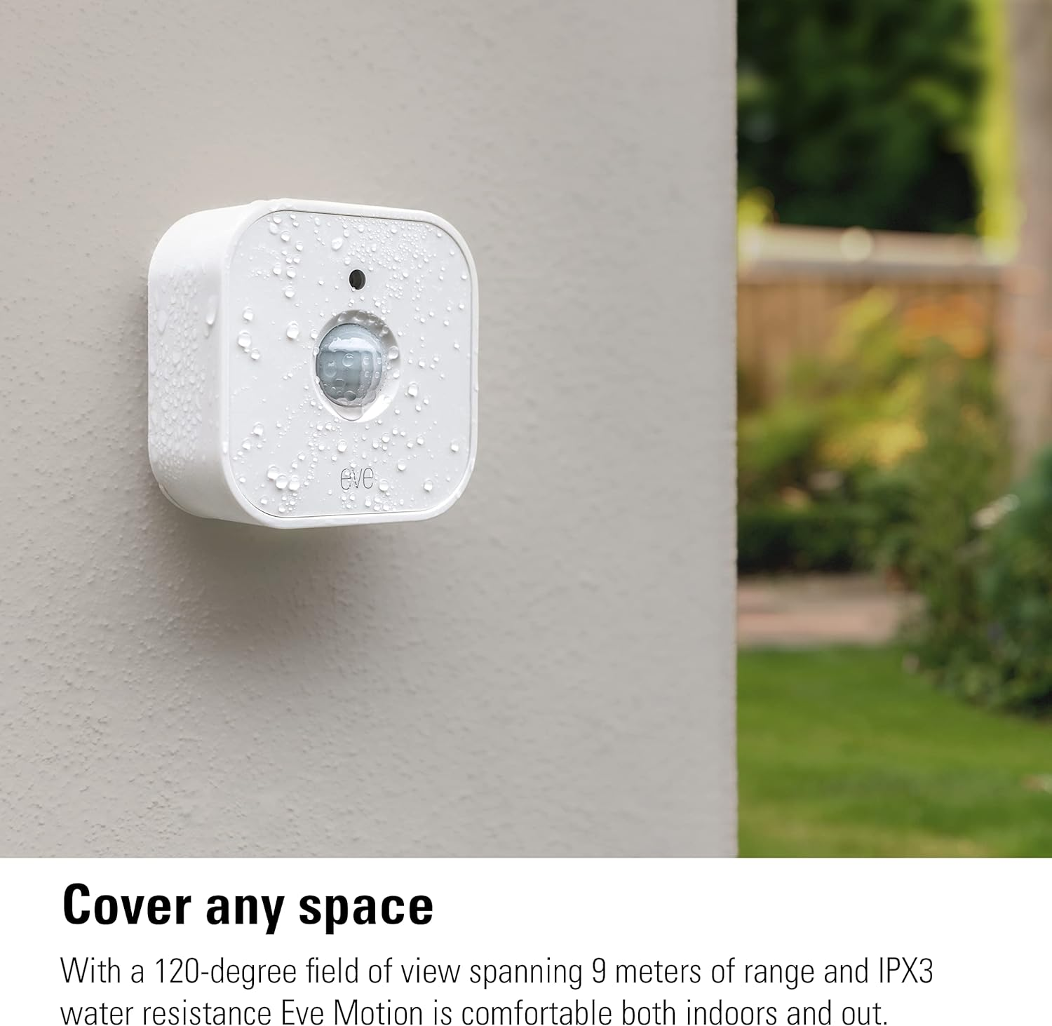 Ein weißer Eve Motion Sensor mit Wassertropfen ist an einer strukturierten Wand montiert. Grüne Außenbereiche sind sichtbar.