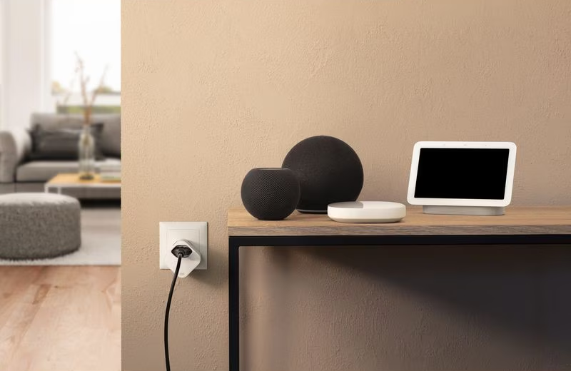 Zwei smarte Lautsprecher, ein Display und ein Stecker an der Wand.