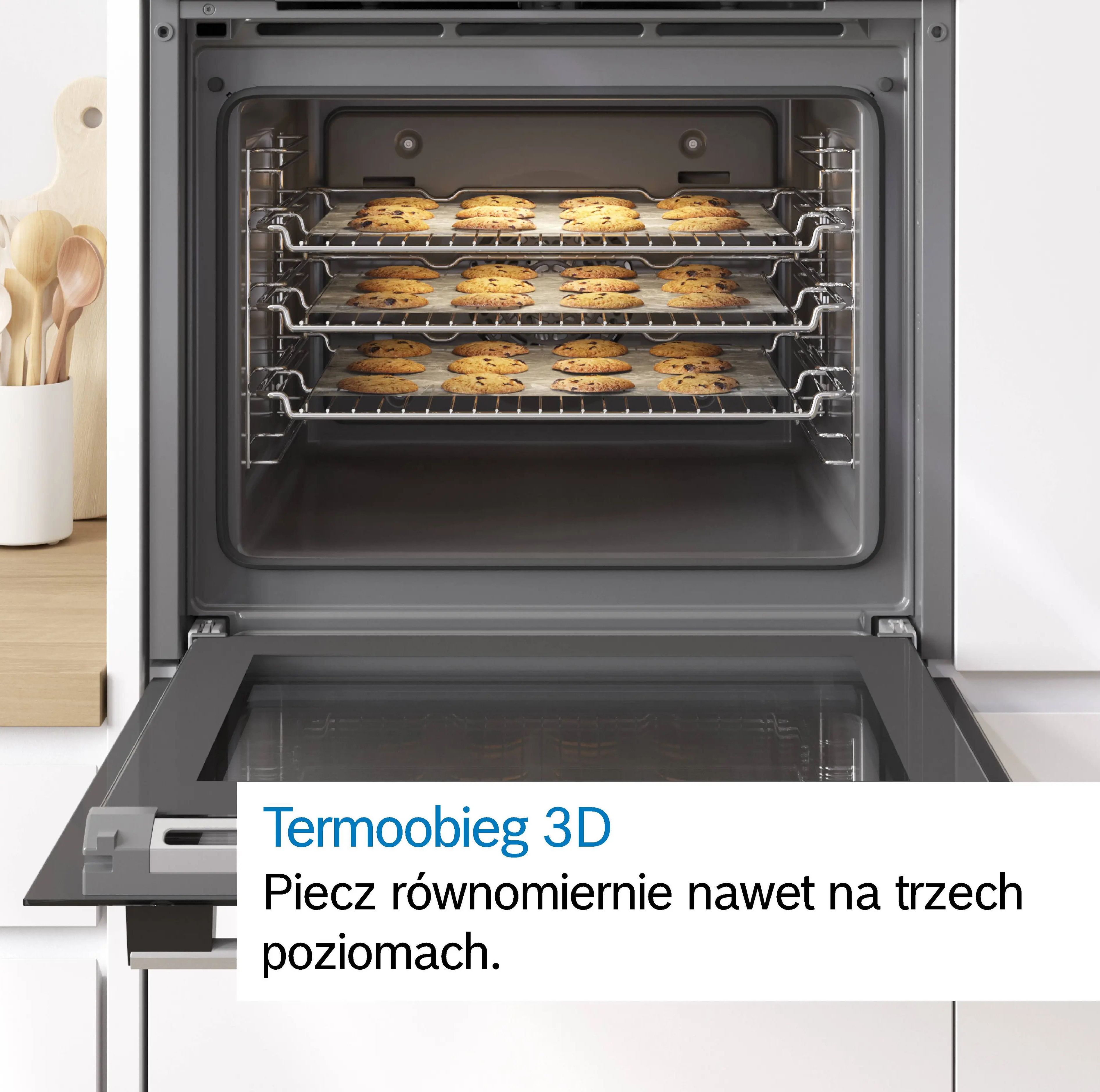 Piekarnik z trzema blachami ciastek. Drewniane przybory po lewej.