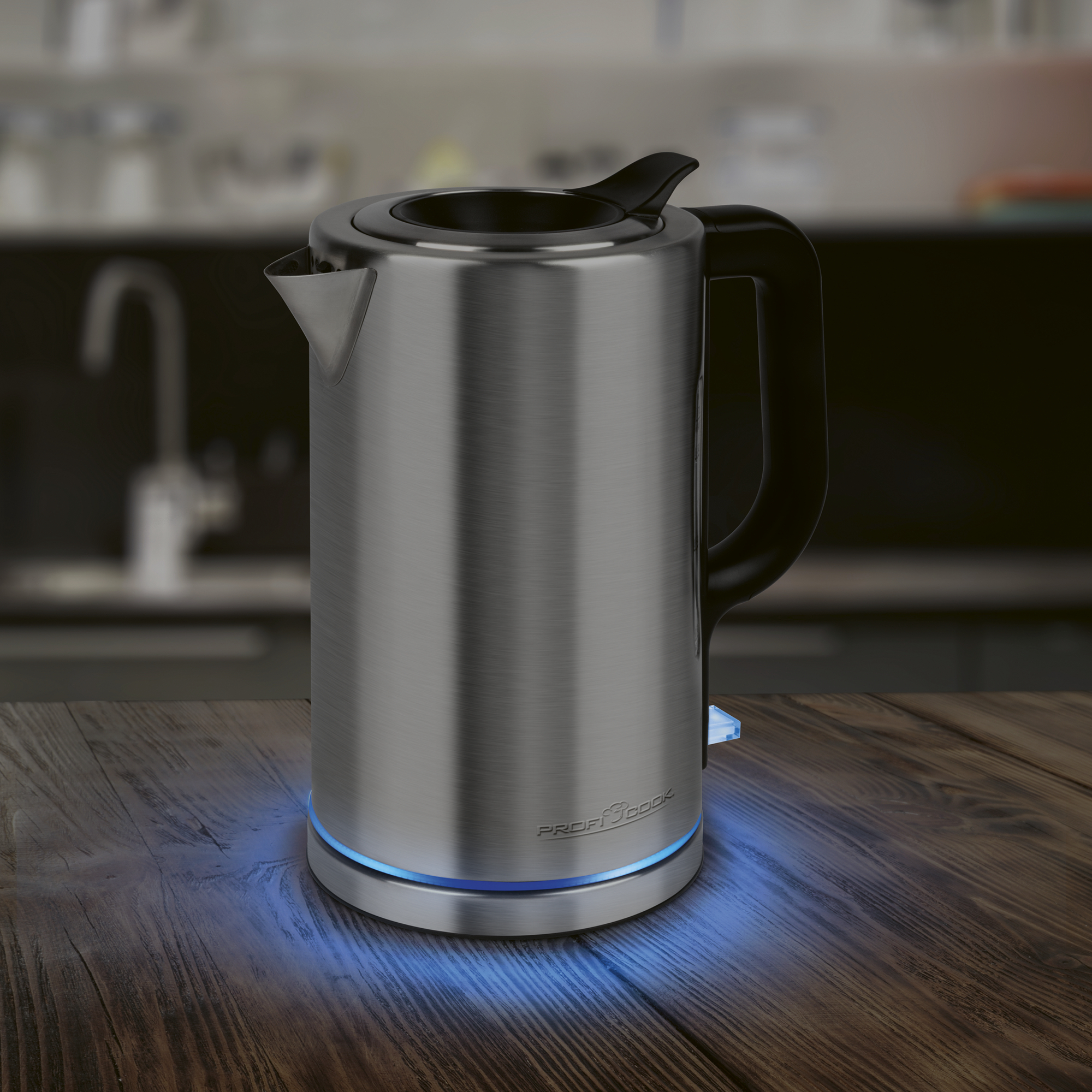 Ein silberner Wasserkocher mit schwarzem Griff steht auf einem Holztisch. Blaue Lichter leuchten darunter.