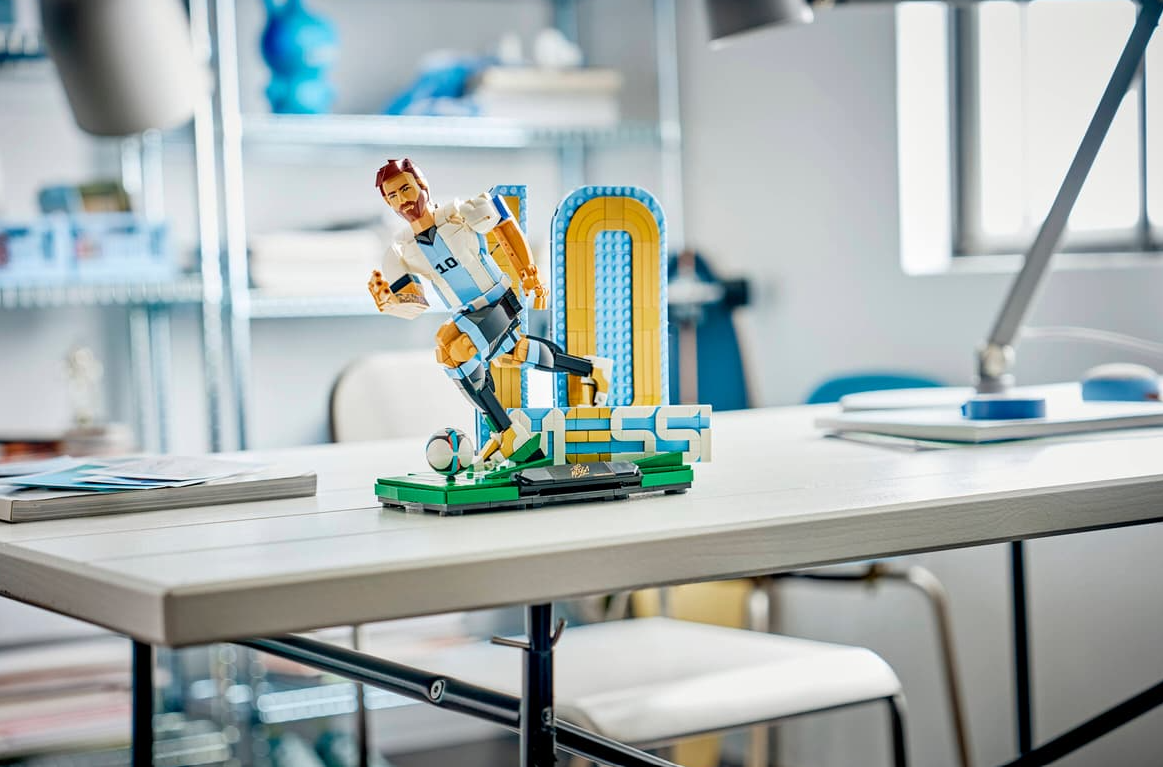 Ein Lego-Modell von Lionel Messi in Aktion, auf einem Schreibtisch.