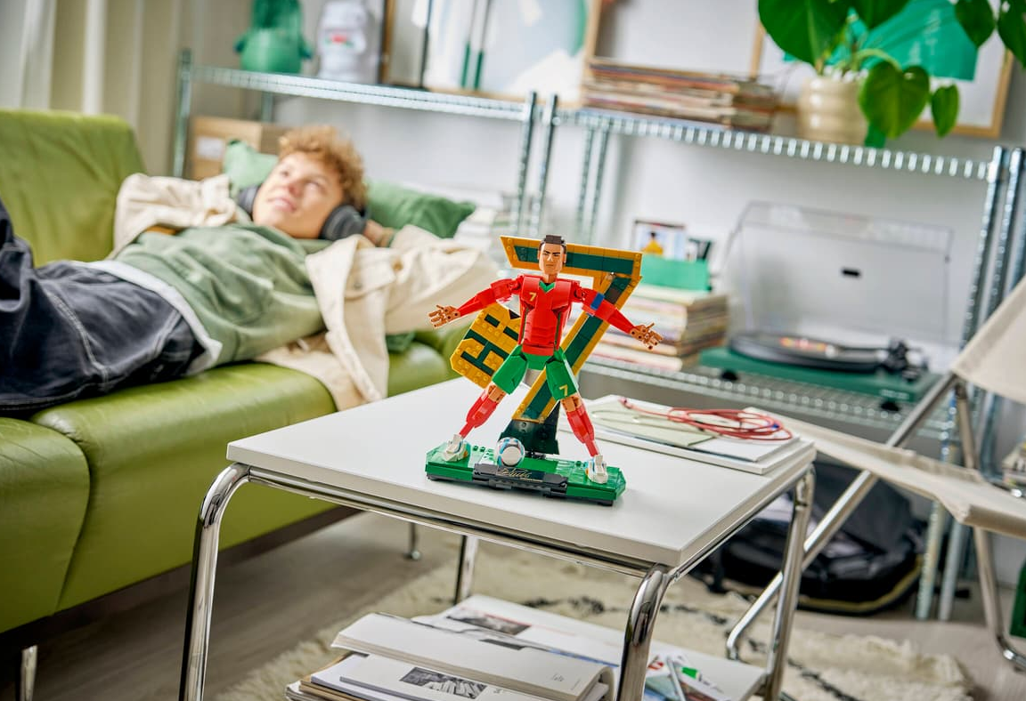 Ein Junge liegt auf einem grünen Sofa und hört Musik. Ein Cristiano Ronaldo Lego-Set steht auf einem Tisch.