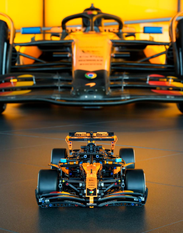 Ein Lego-Modell eines McLaren F1-Autos in Orange und Schwarz steht vor einem unscharfen, vollformatigen orangefarbenen F1-Auto.