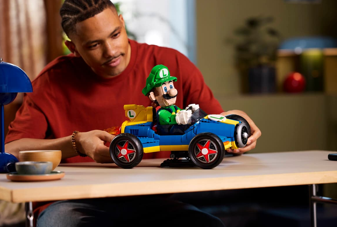 Ein Mann baut einen blauen und gelben Lego-Rennwagen mit Luigi.