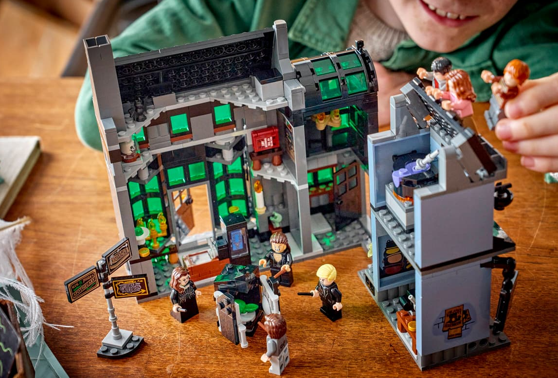 Ein Kind spielt mit einem detailreichen Lego Harry Potter Set, das ein Gebäude mit Minifiguren zeigt.