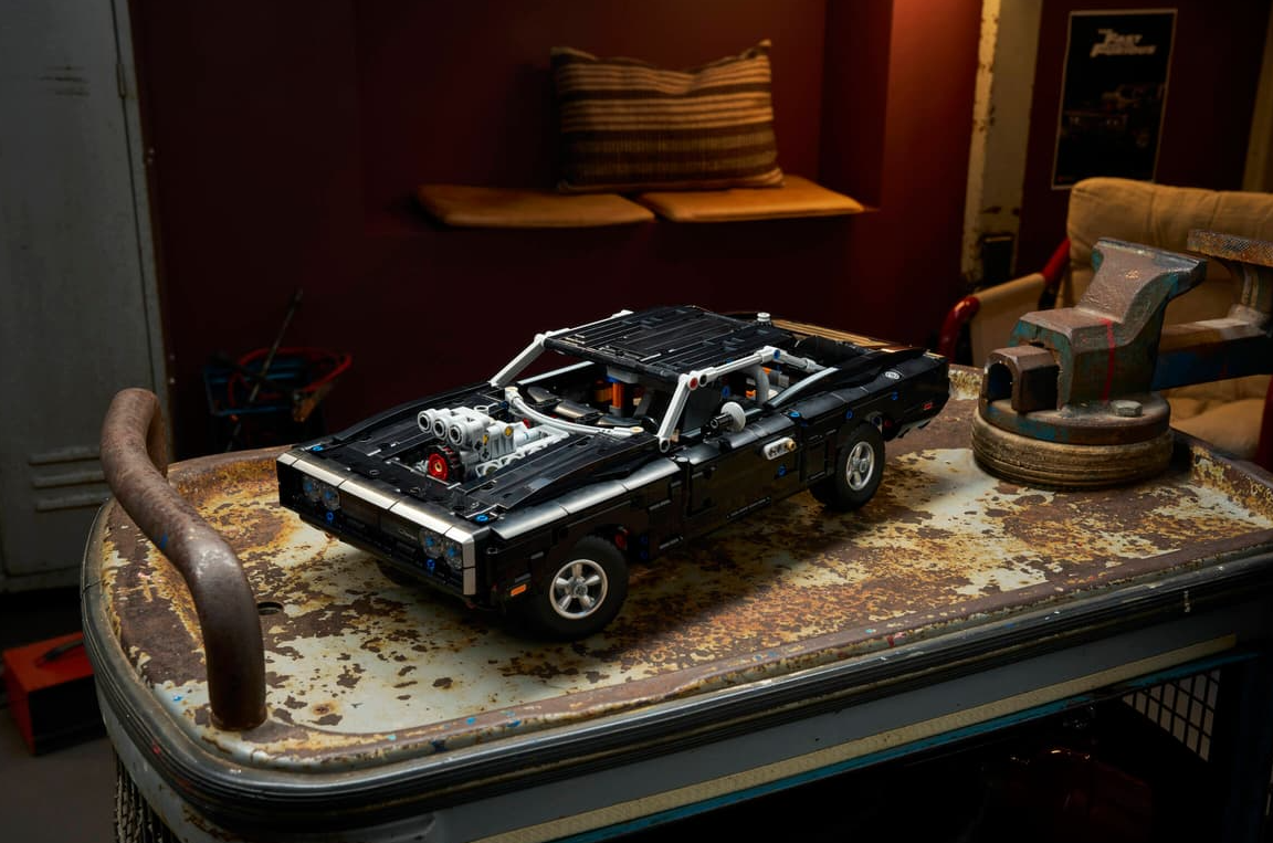 Schwarzer Lego-Sportwagen mit freiliegendem Motor auf einem alten Metallwagen.