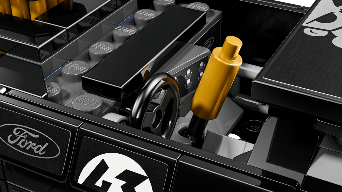 Nahaufnahme eines goldenen Lego-Teils neben einem schwarzen Lenkrad und Ford-Logo.