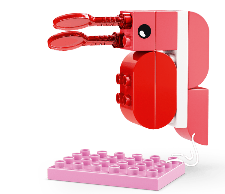 Ein rosafarbener Lego-Krebs mit roten Zangen und einem schwarzen Auge auf einer rosa Platte.