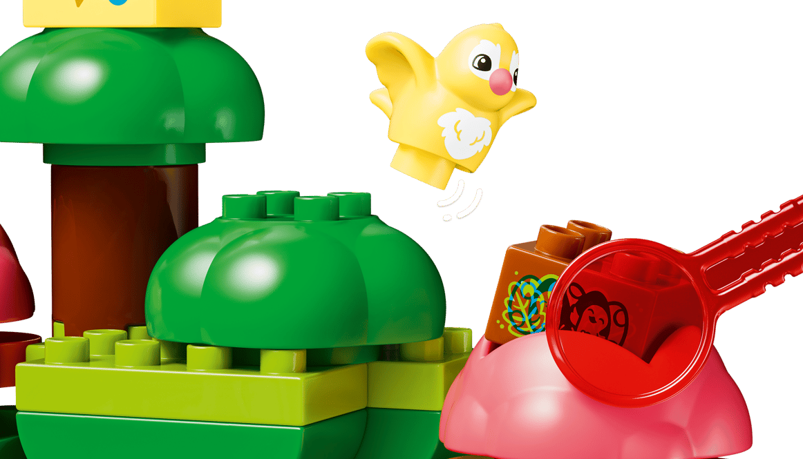 Bunte Bausteine bilden einen Baum und eine Figur. Ein gelber Vogel fliegt.